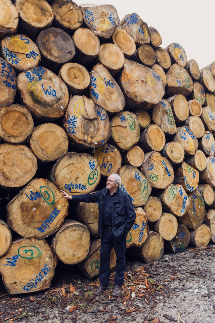 Eckhard Wolf vor Rundholzstapel