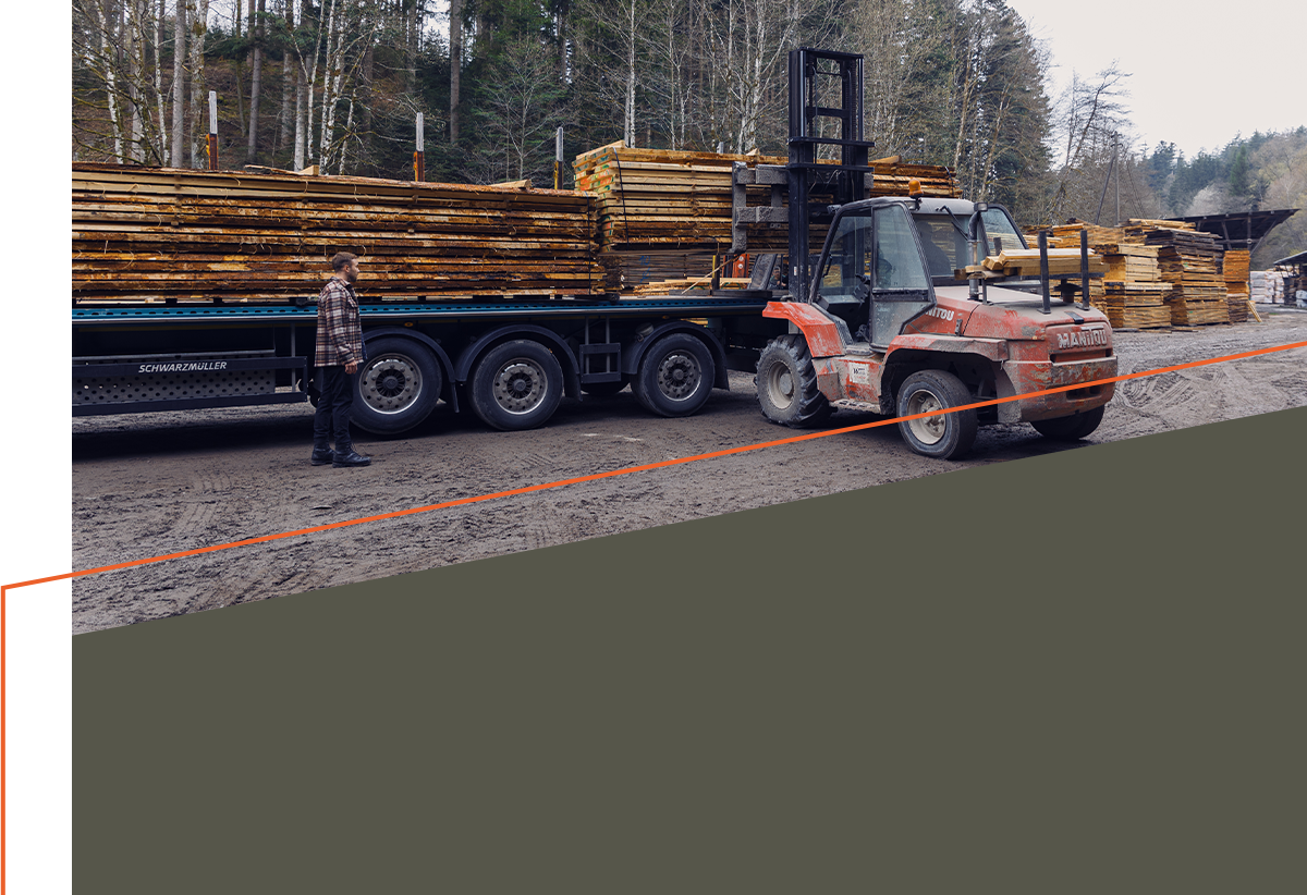 Ein Gabelstapler stapelt Schnittholz auf einen LKW-Anhänger.