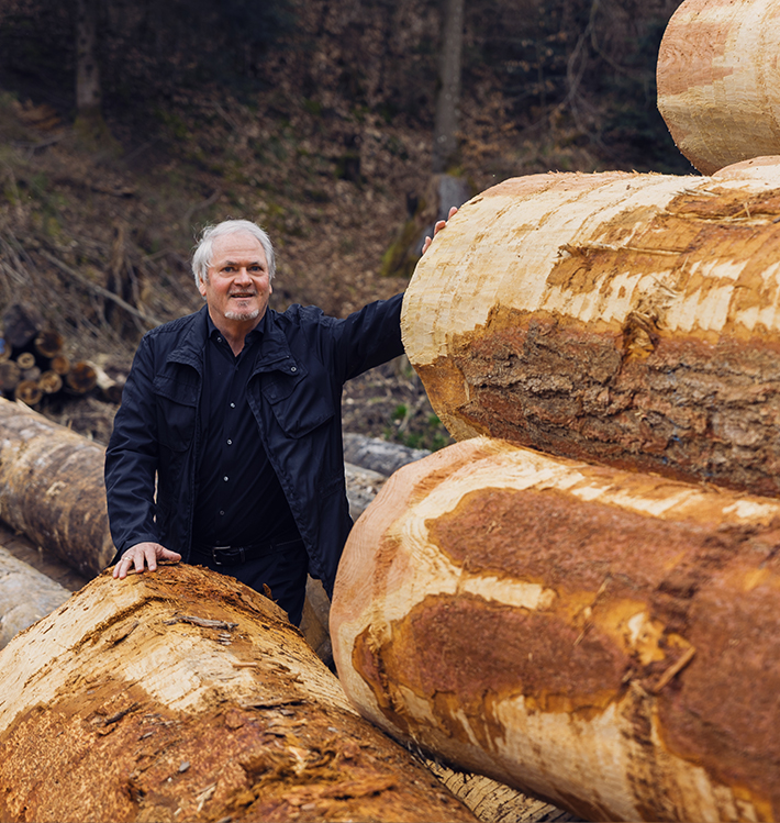 Eckhard Wolf hinter Rundholzstapel