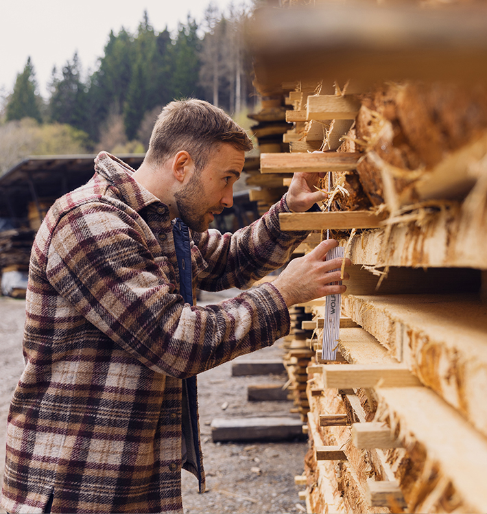 Jonas Luddeneit prüft Holzbretter mit Maßstab