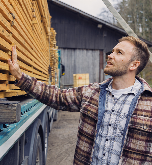 Jonas Luddeneit prüft Schnittholz auf einem LKW-Anhänger.