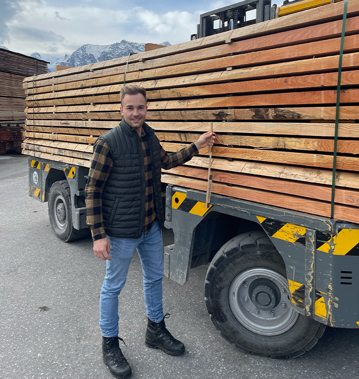 Jonas Luddeneit neben einem Transporter mit Schnittholz-Ladung.